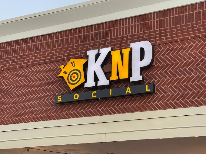 Sign for KNP Social with a target logo on a brick wall.