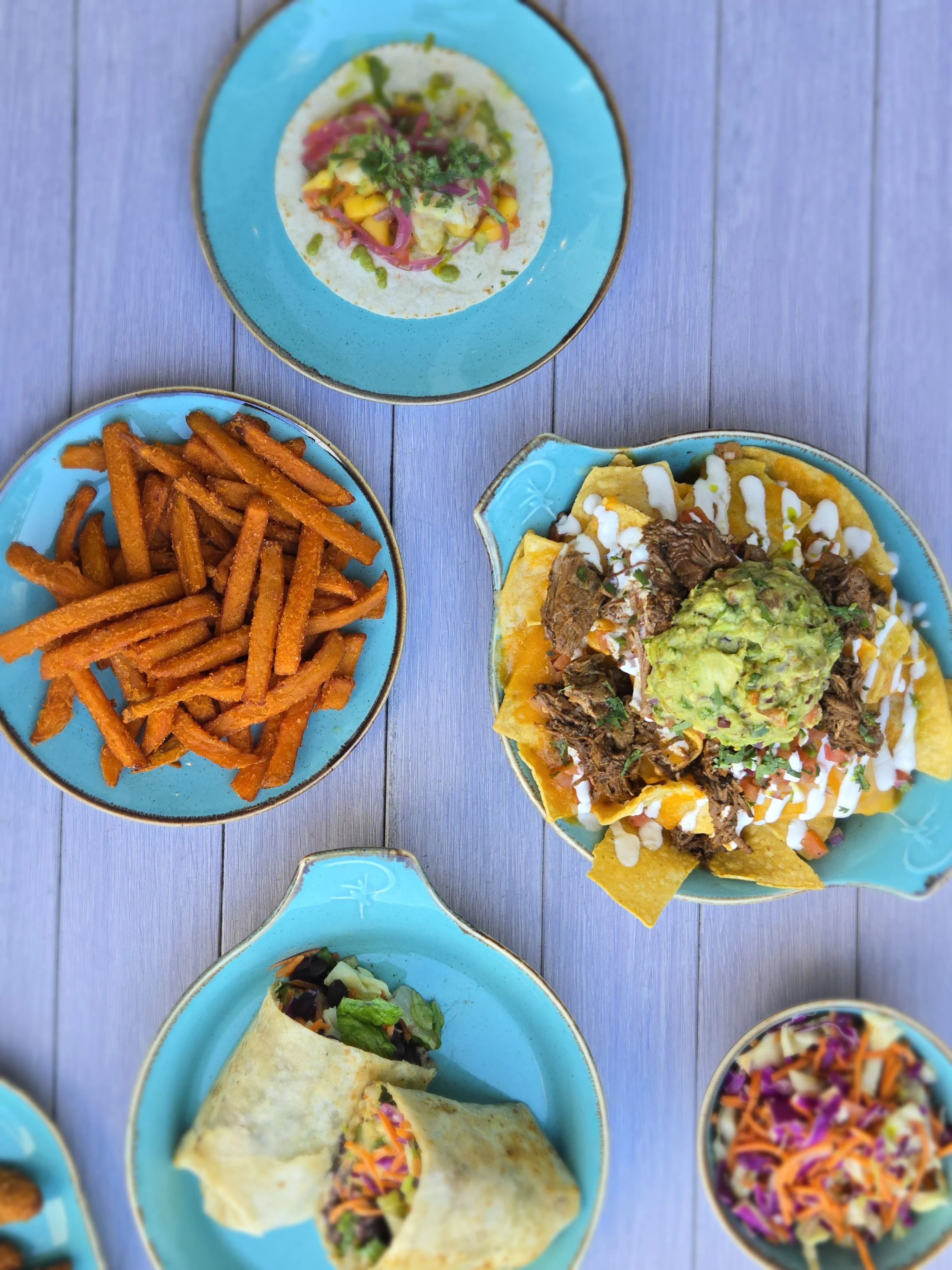 Colorful Mexican nachos with guacamole and tacos on a vibrant table