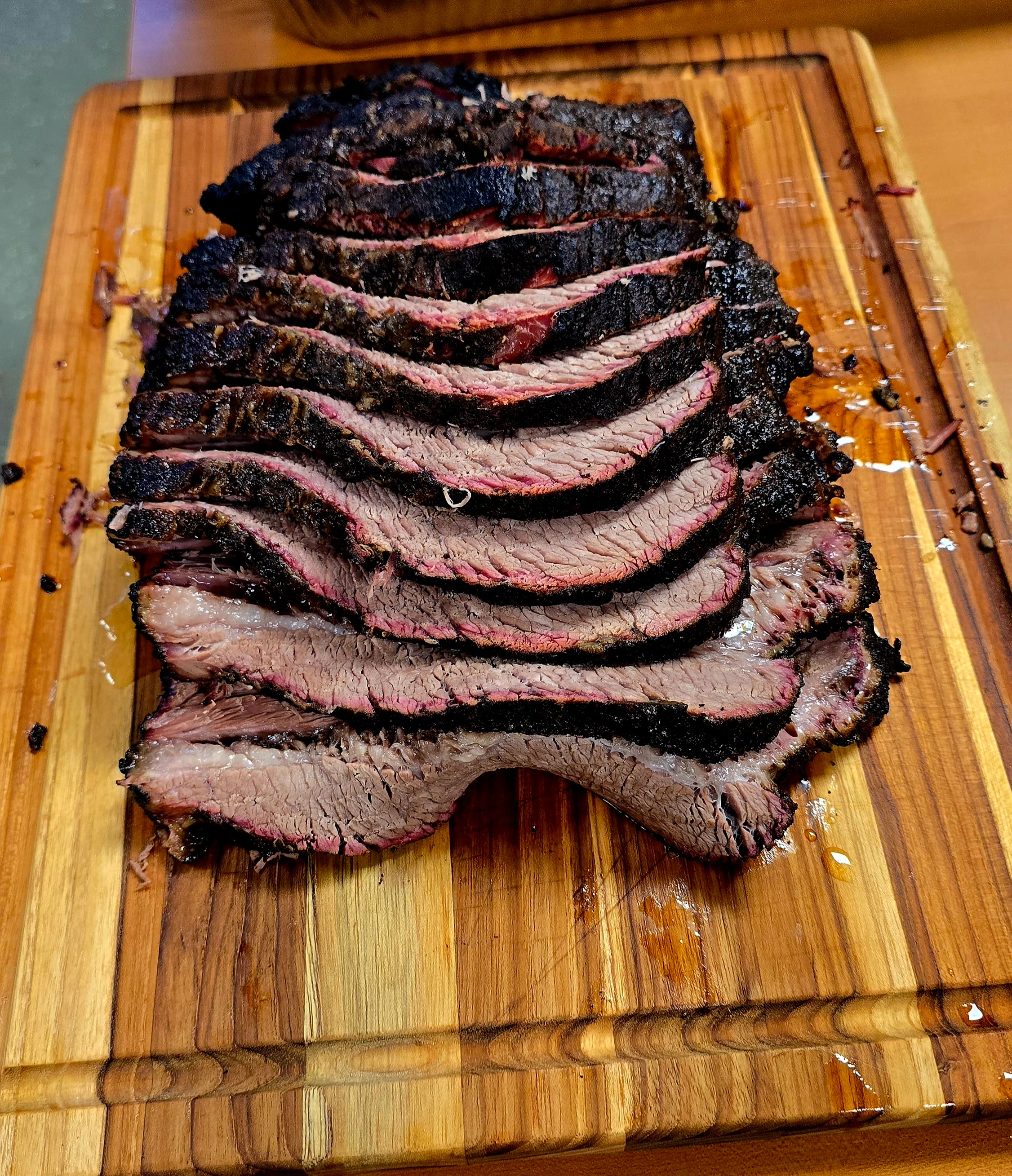 Sliced Texas-style smoked brisket on a wooden cutting board