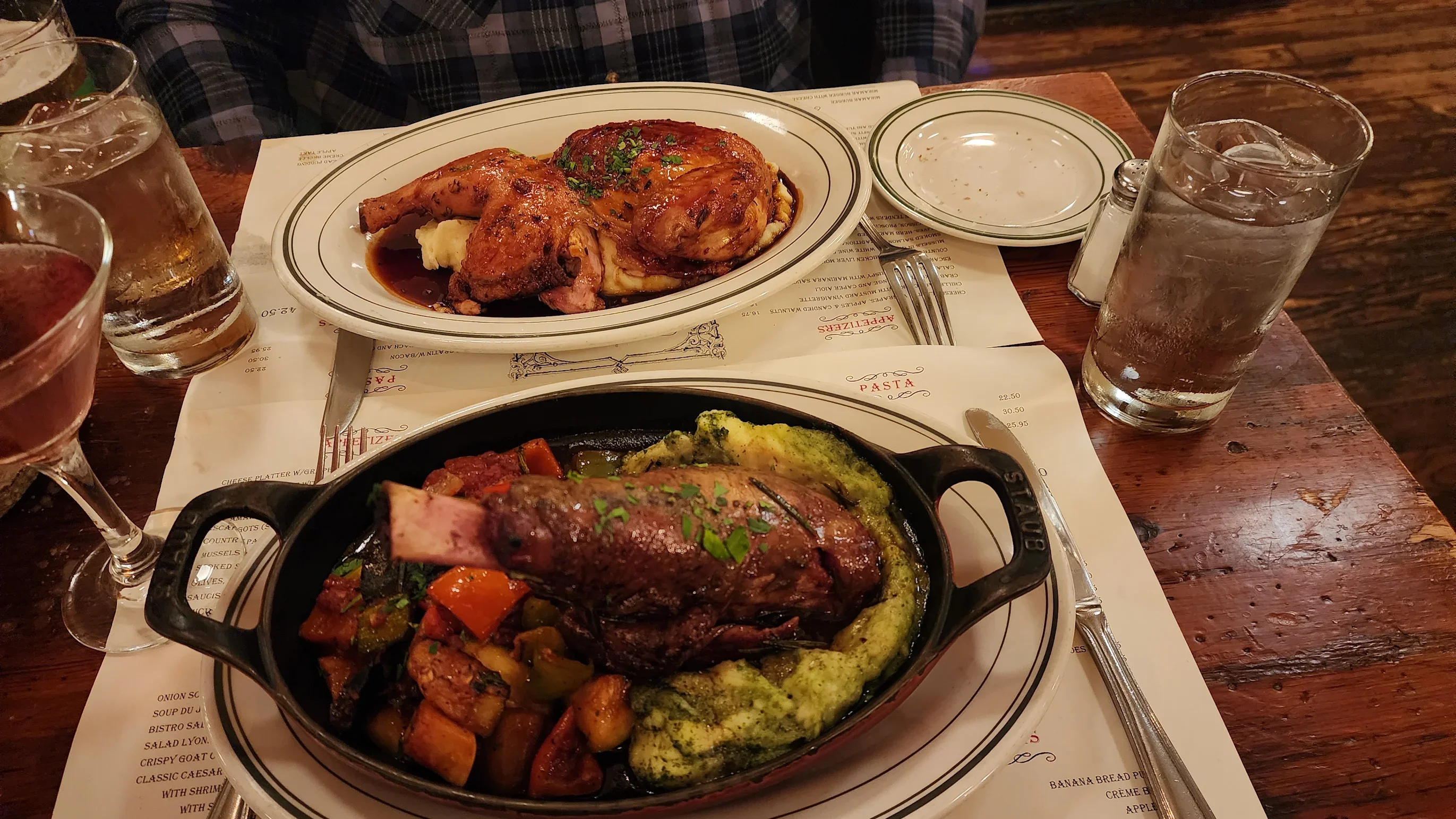 Hearty American roast chicken and lamb shank with vegetables on a rustic table