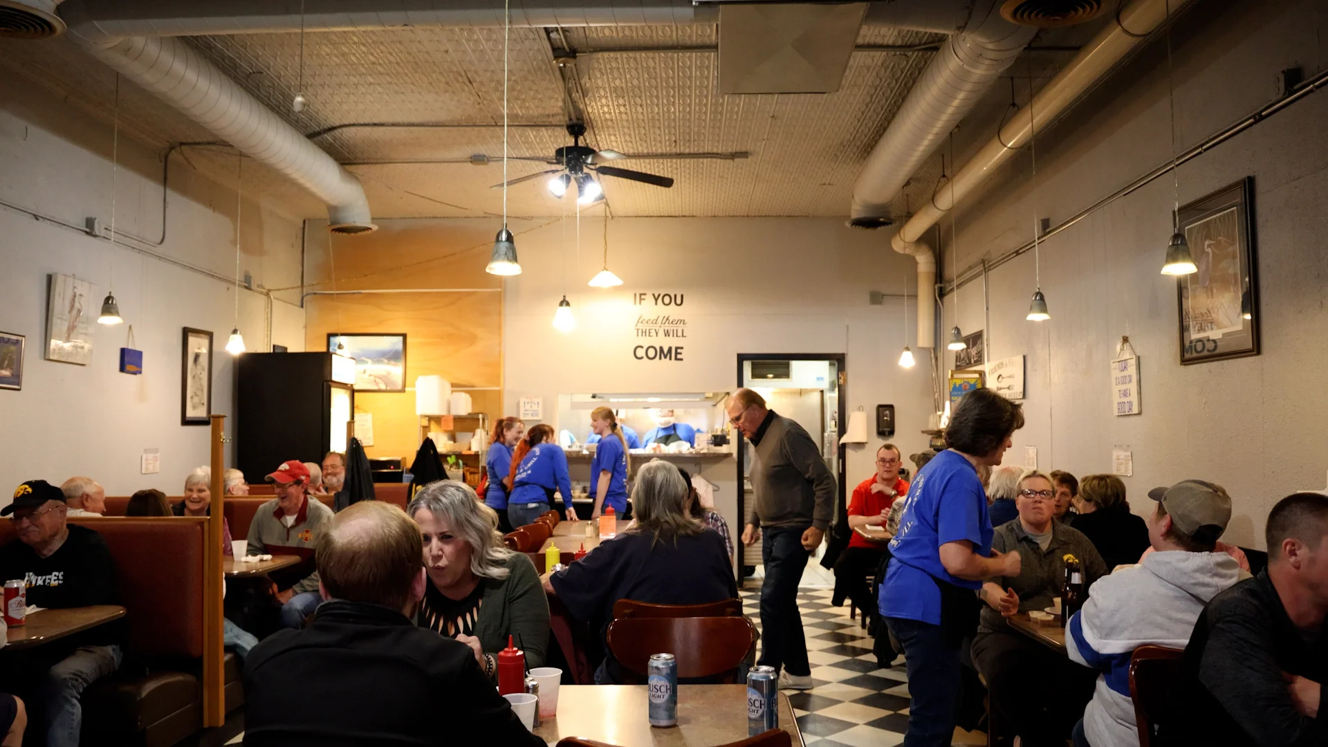 Busy restaurant interior with patrons dining and staff serving food.