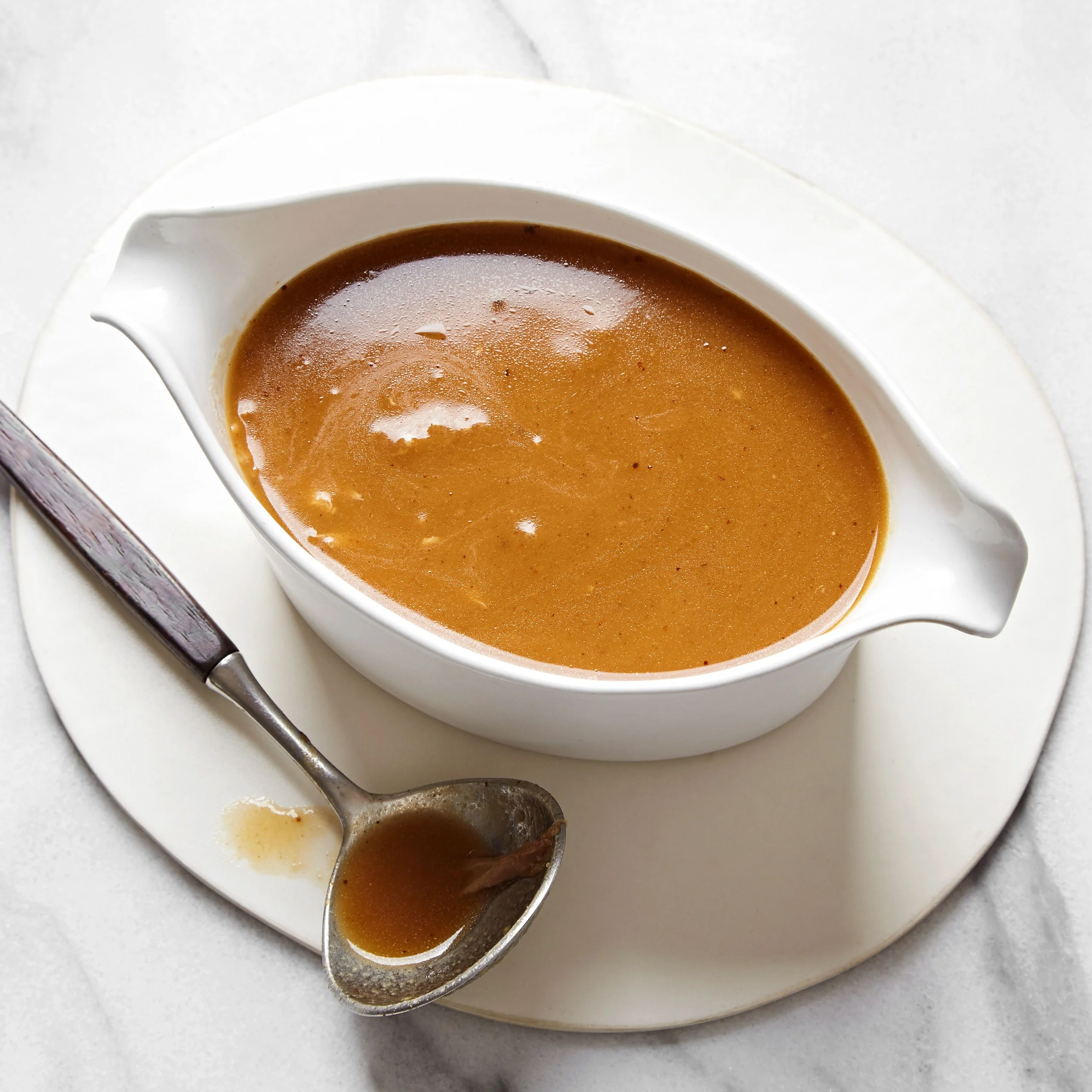 Rich brown gravy in a white serving dish with a spoon.
