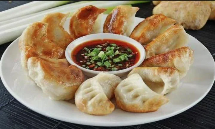 Plate of crispy Chinese potstickers with dipping sauce