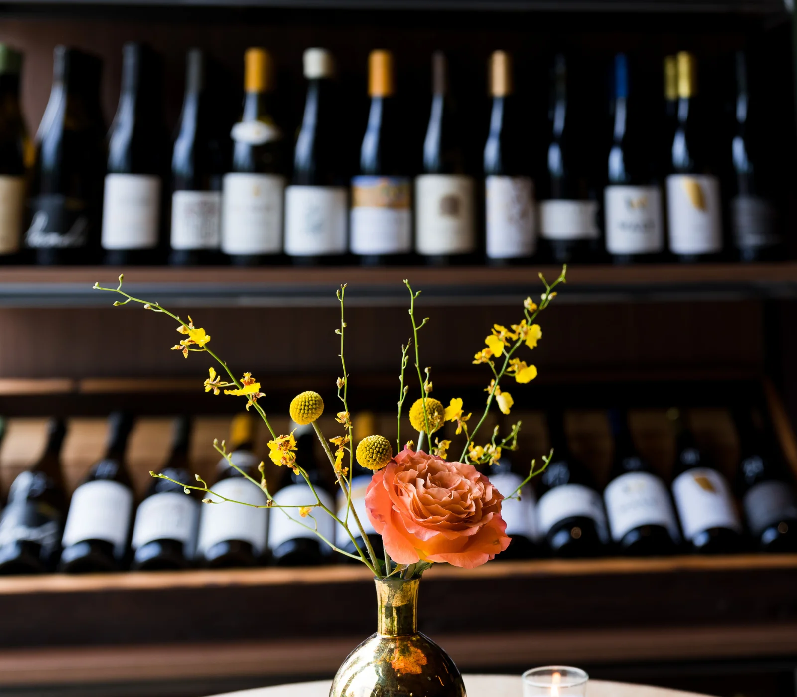 Elegant restaurant table with floral centerpiece and wine bottles in the background