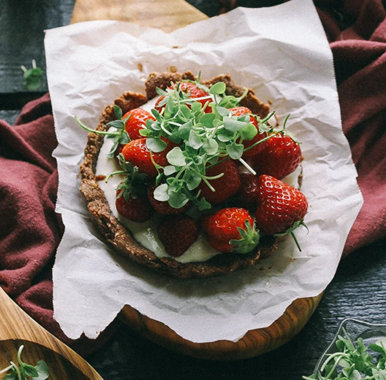 Fresh strawberry tart with microgreens on a rustic wooden table
