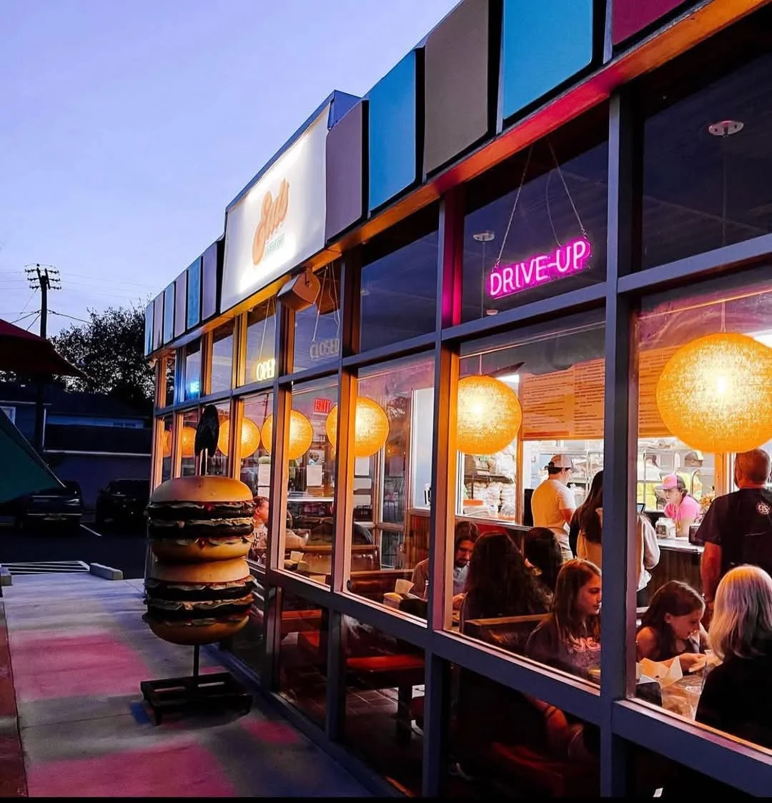 Vibrant restaurant exterior with neon signs and a giant burger display