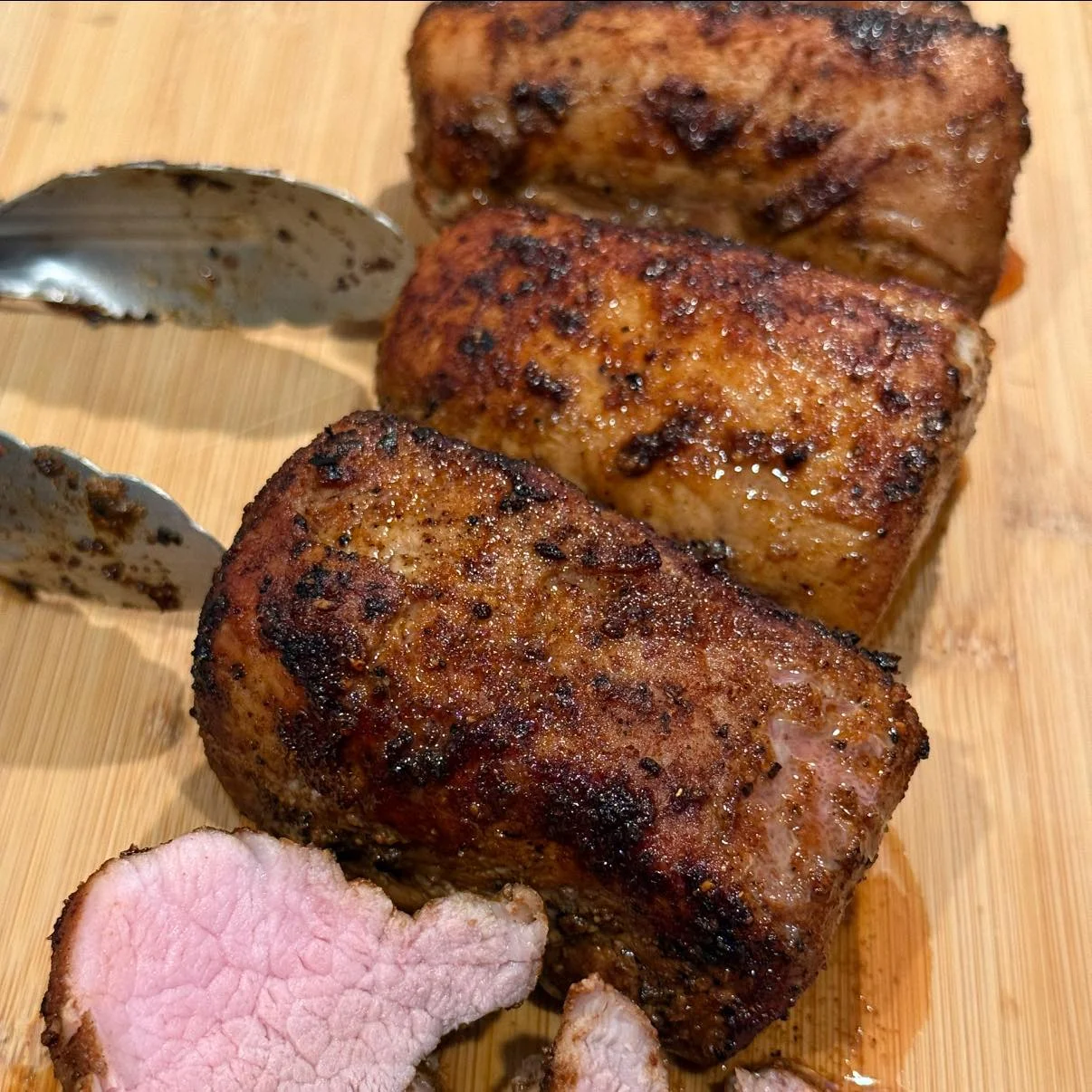 Grilled pork tenderloin slices on a wooden board