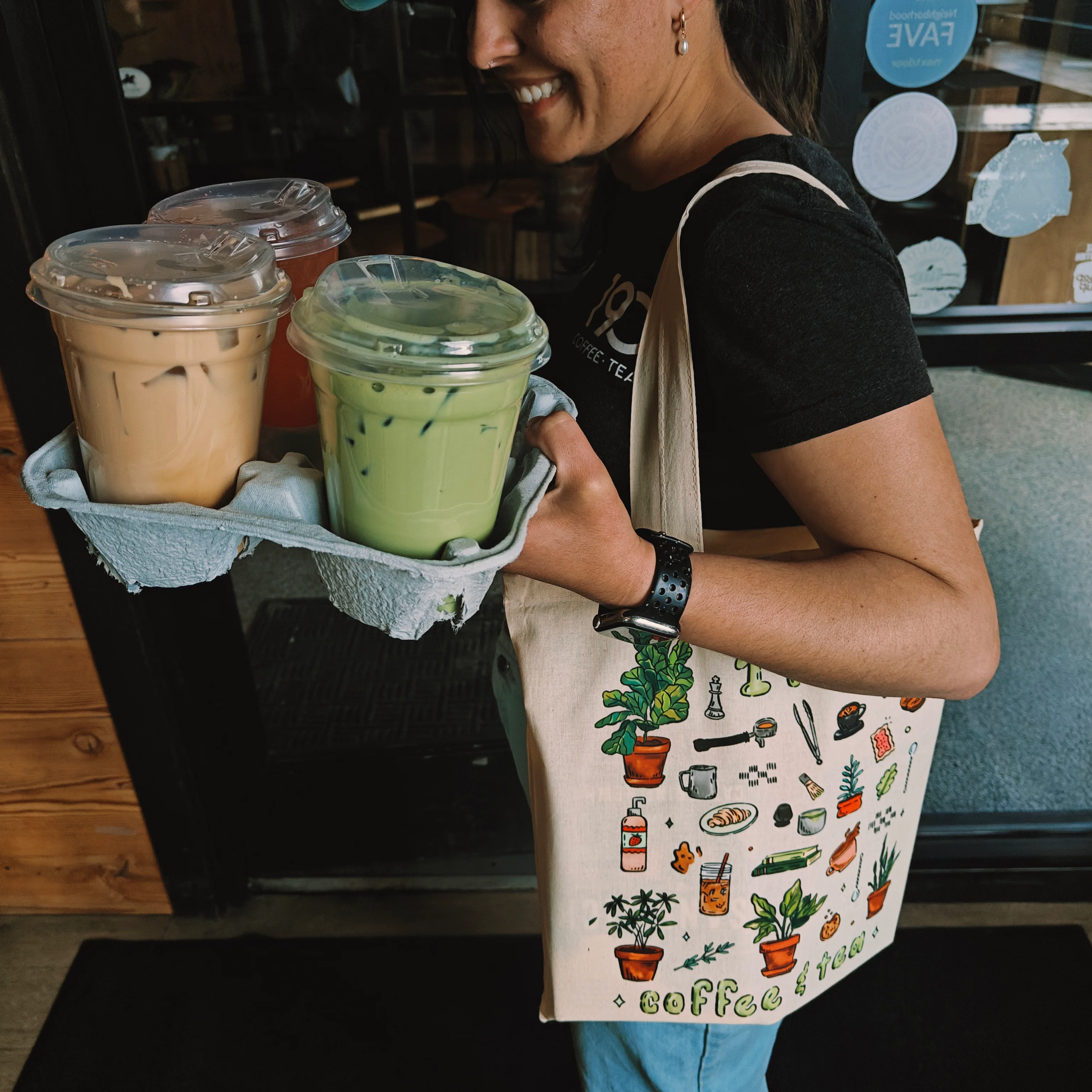 Person carrying iced drinks in a cozy café setting