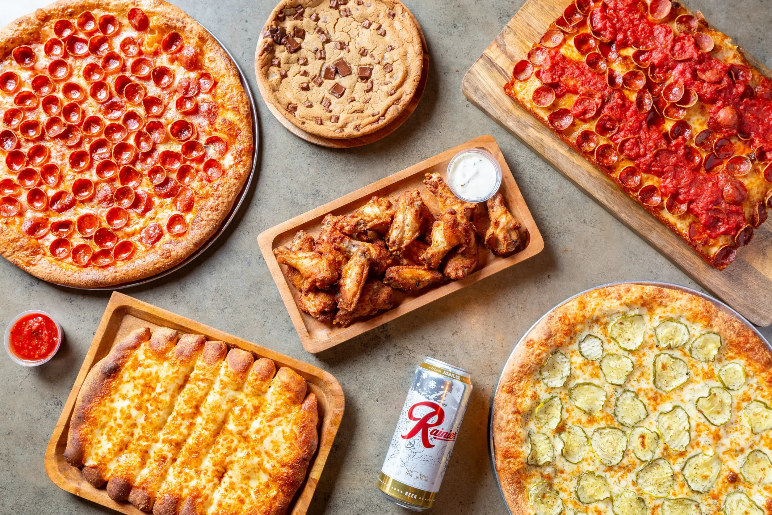 Variety of pizzas and wings on a rustic table