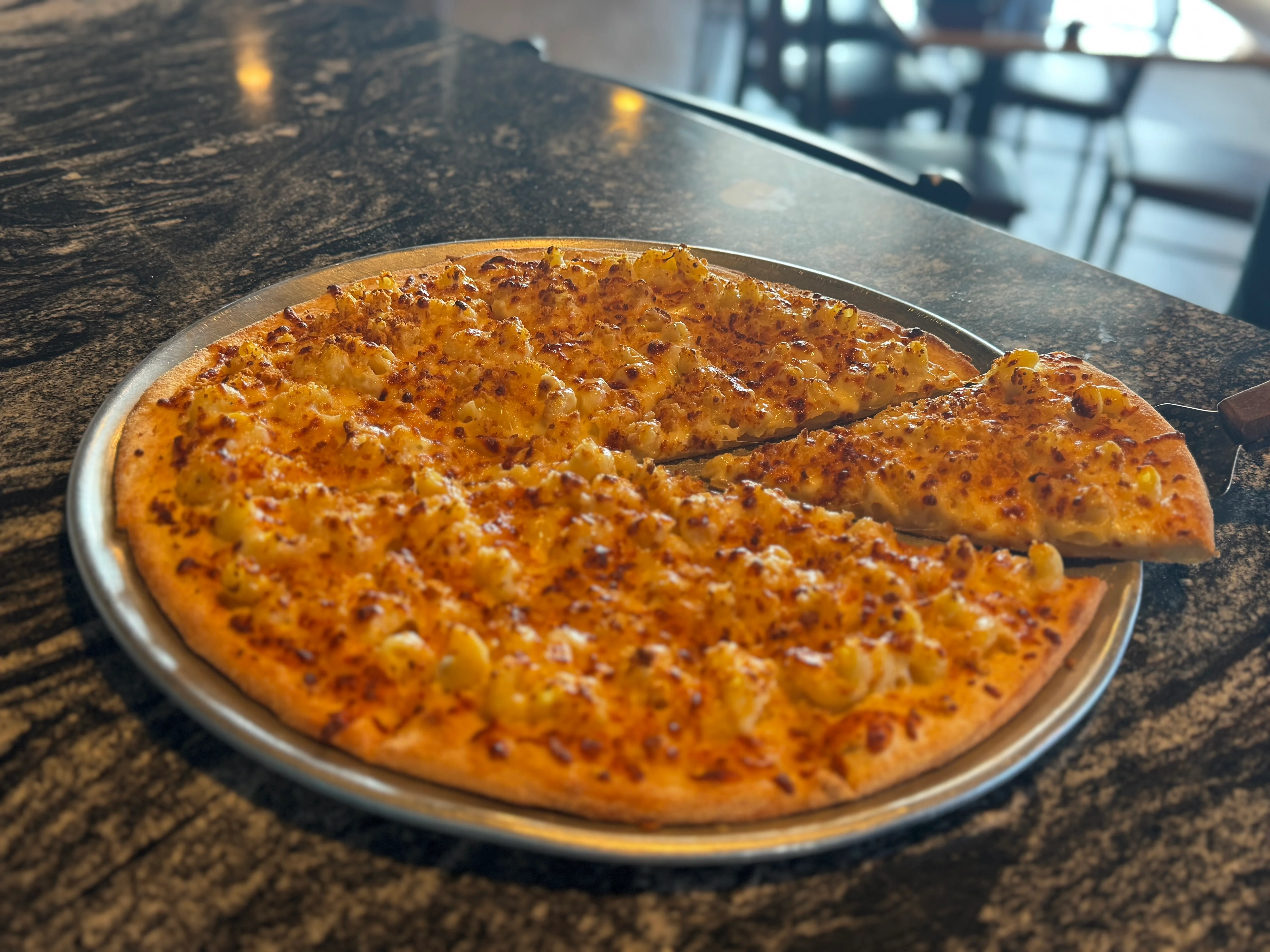 Cheesy macaroni pizza on a silver platter