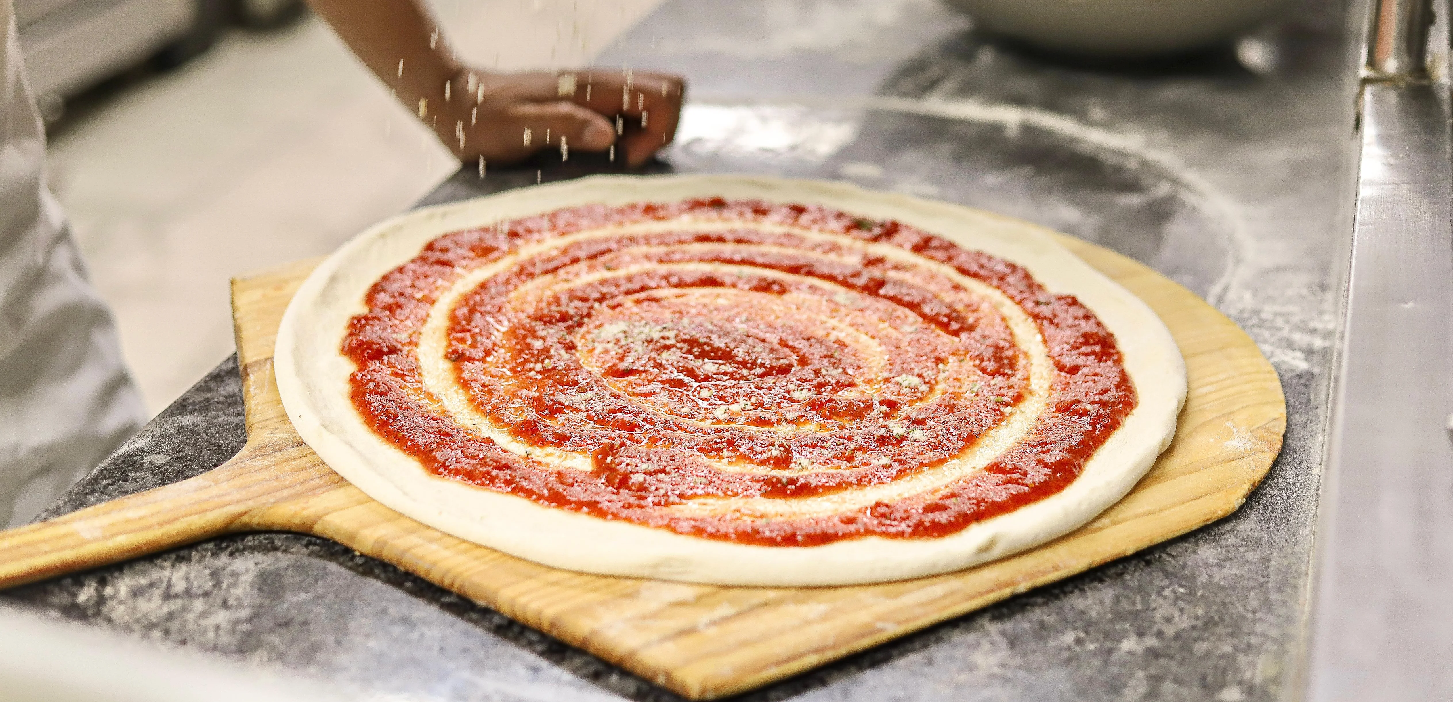 Preparing Margherita pizza with tomato sauce