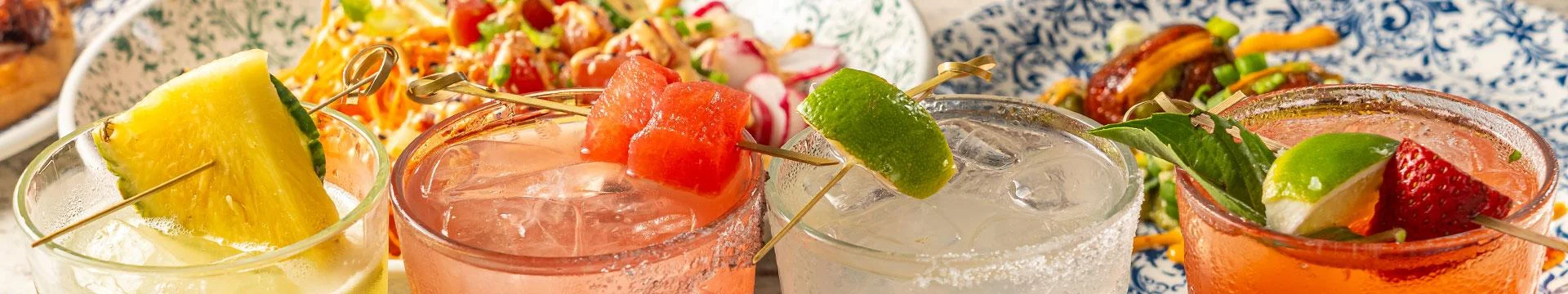 Colorful cocktails garnished with fruit and herbs at a vibrant bar
