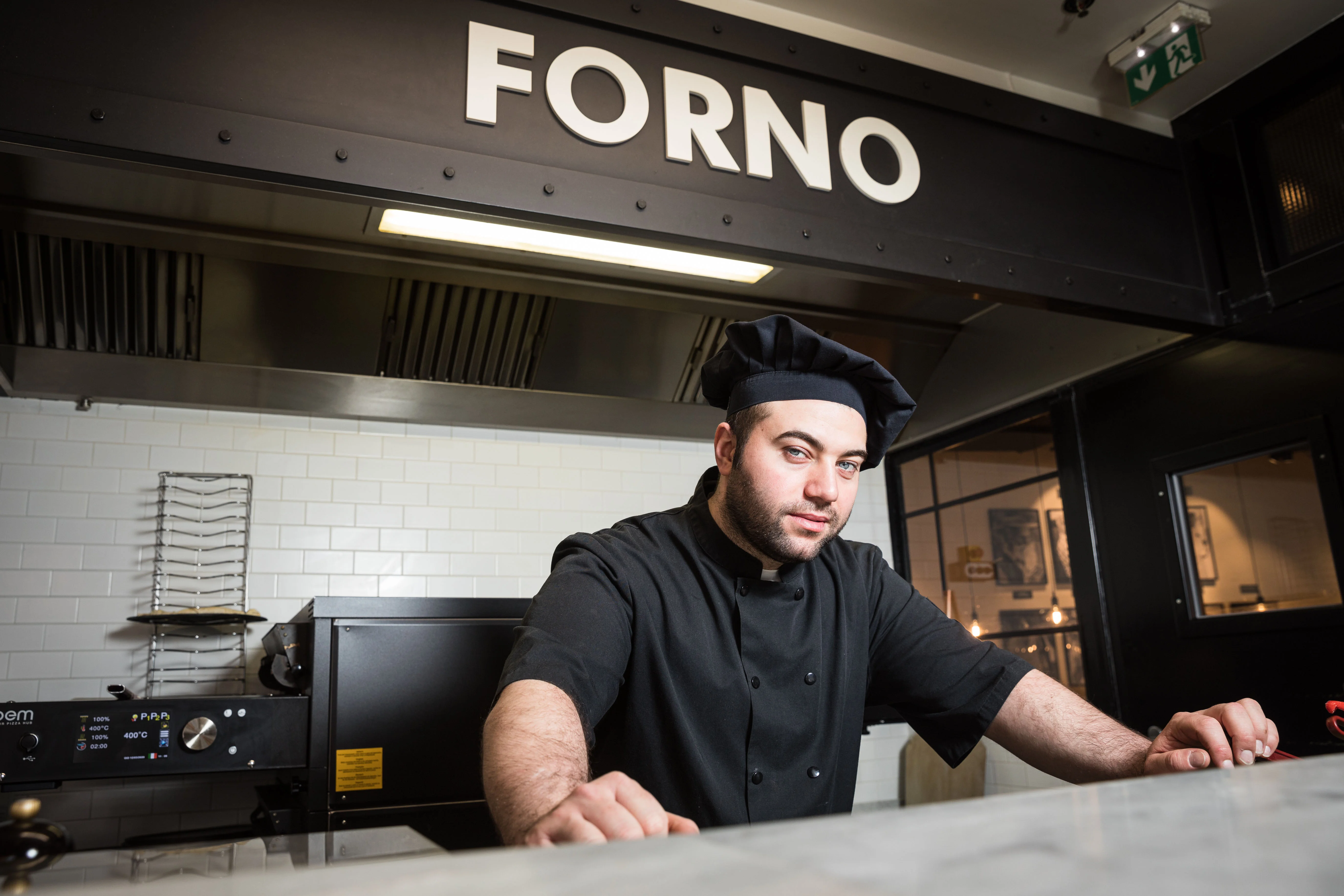 Chef in front of a wood-fired oven at Forno restaurant