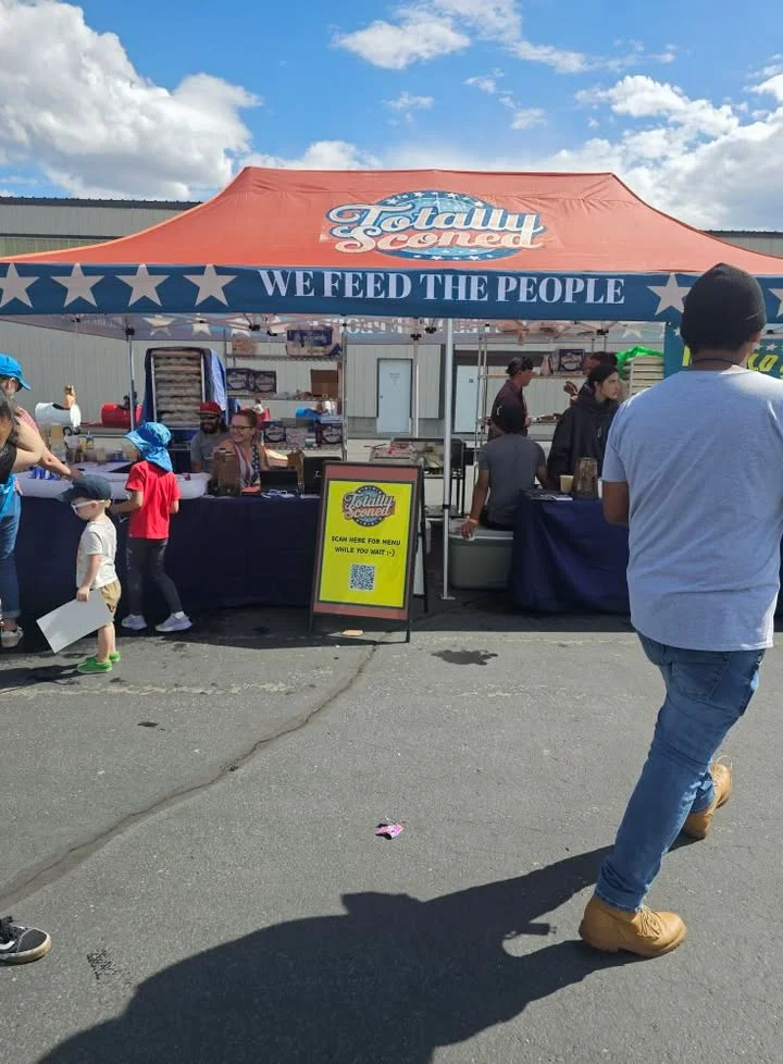 Food stall at a community event with a vibrant tent and menu sign