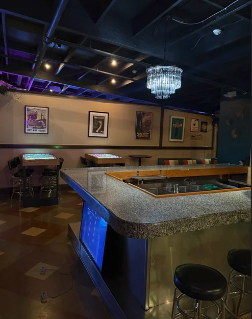 Retro restaurant bar interior with crystal chandelier and illuminated game tables