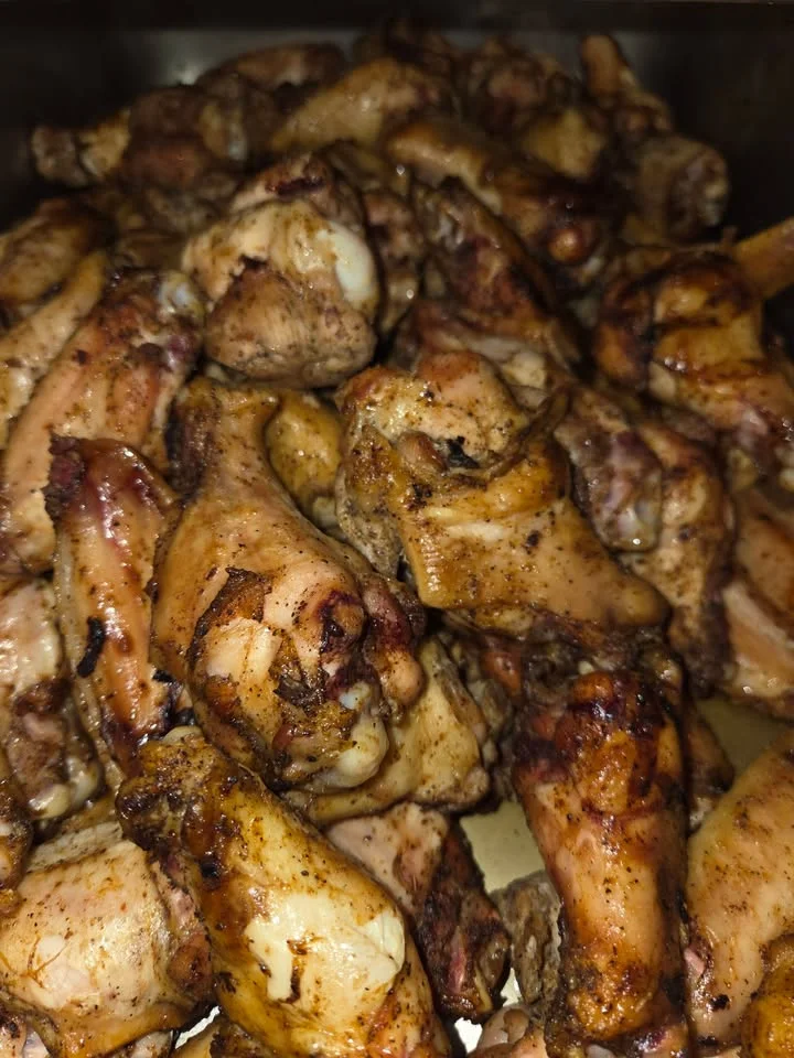 A close-up view of a large pile of grilled chicken wings, showcasing their crispy and seasoned exterior.