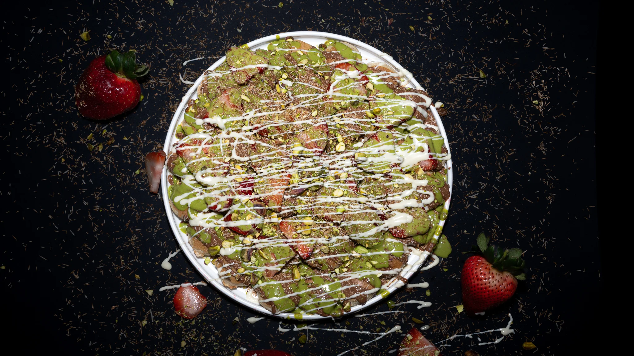 A bowl filled with chocolate-covered treats, topped with crunchy chocolate pieces and drizzled with white chocolate.