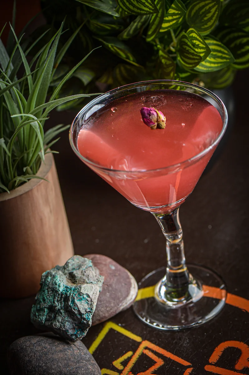 Elegant cocktail garnished with a rosebud in a stylish glass