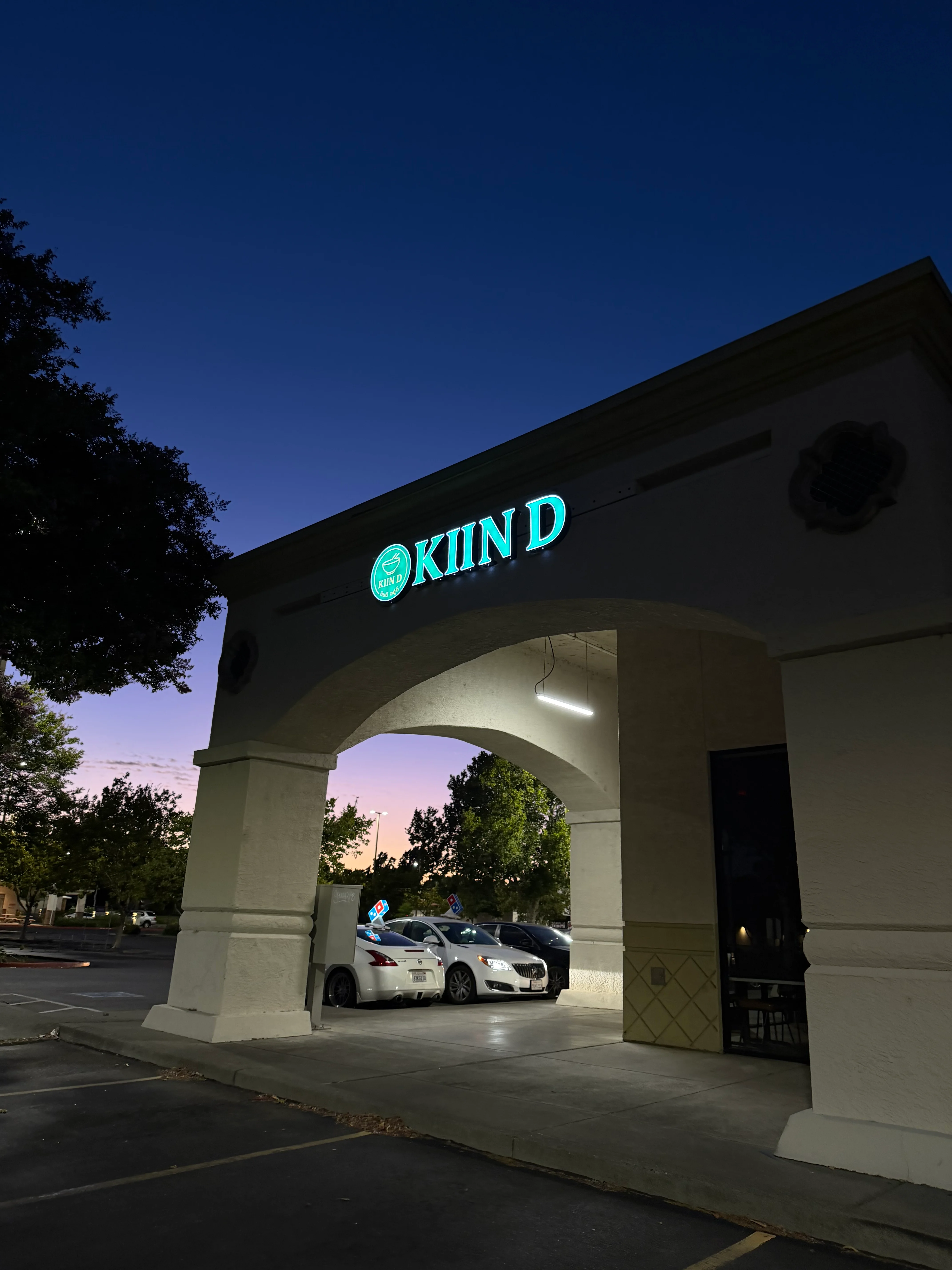Exterior view of Kiin D restaurant at dusk with illuminated signage