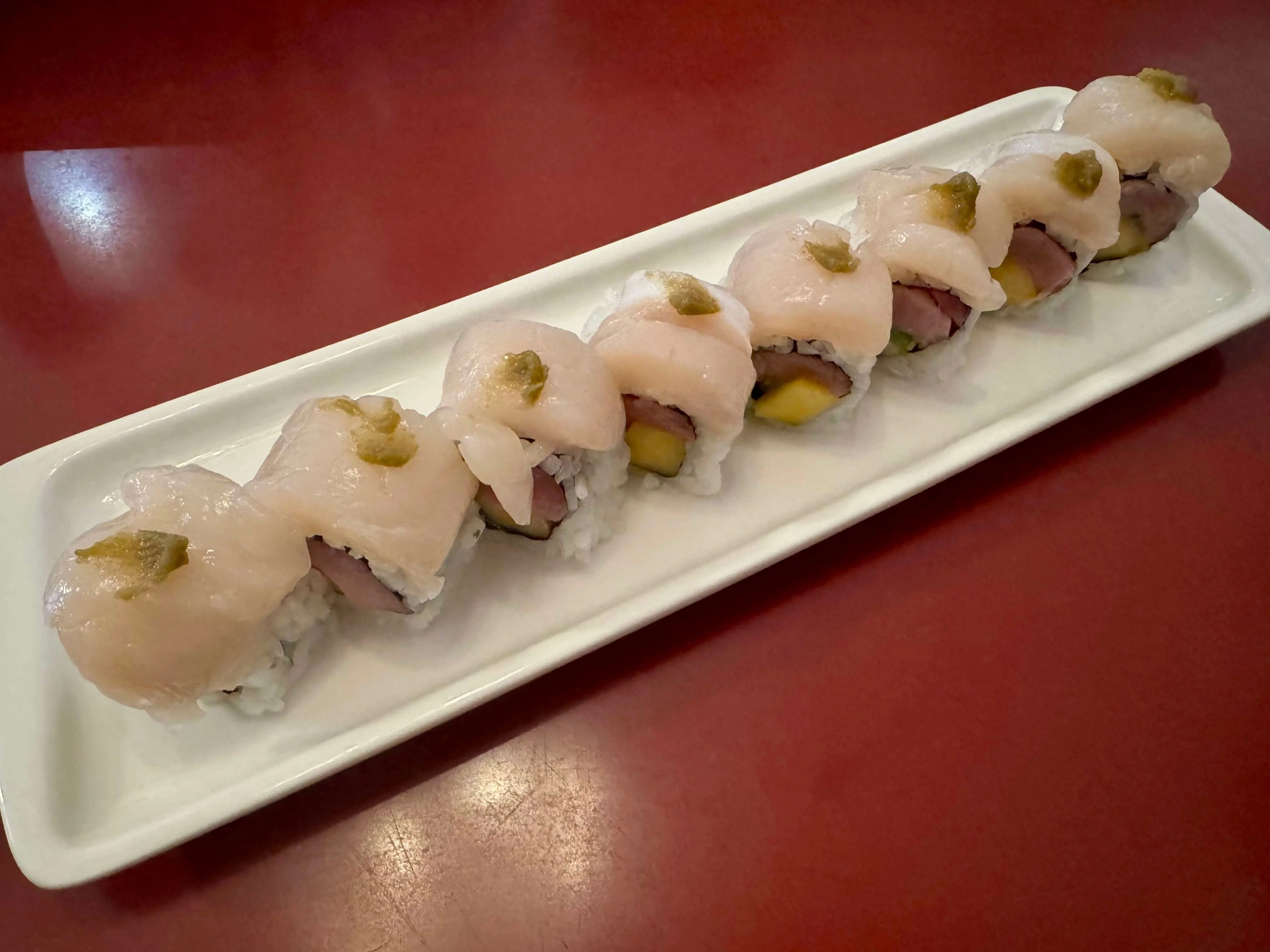Japanese sushi rolls with delicate fish and wasabi garnish on a white plate