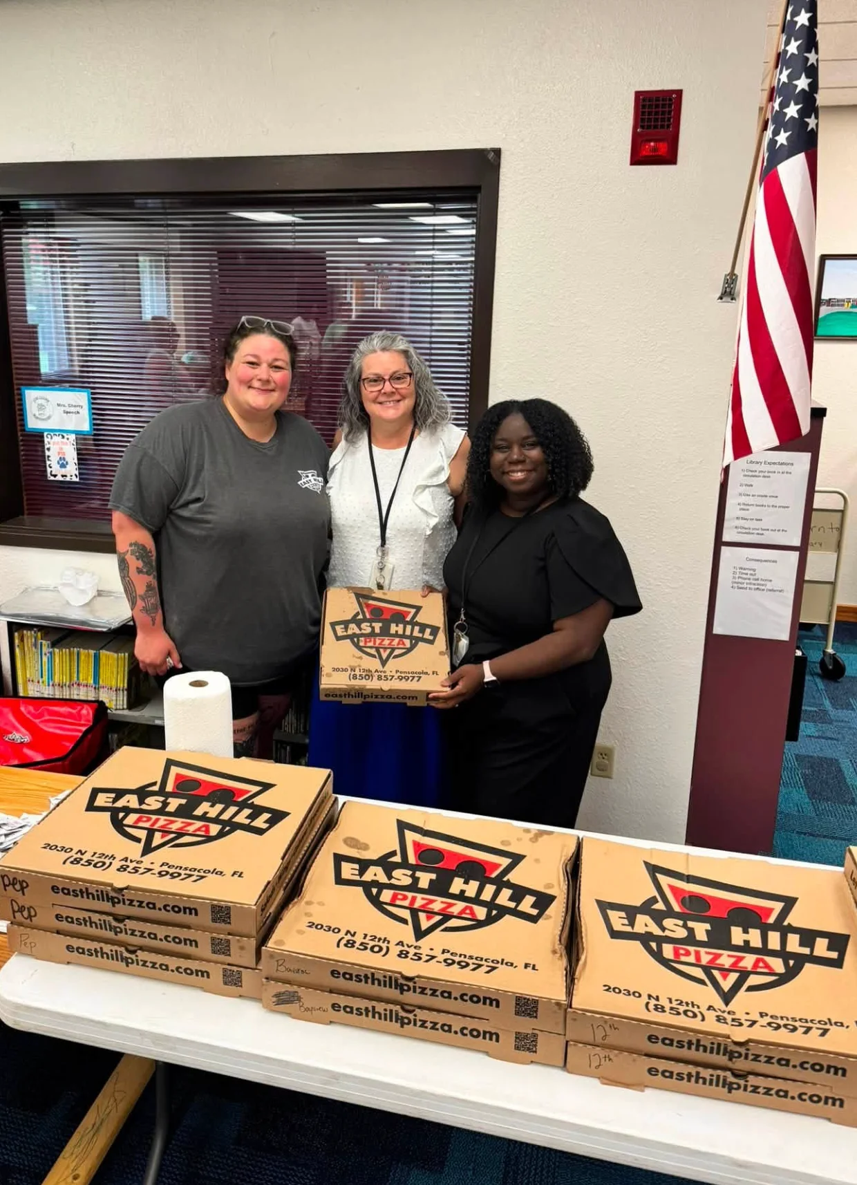 Restaurant staff posing with branded pizza boxes at a community event