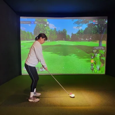 Woman practicing golf swing in a virtual simulator