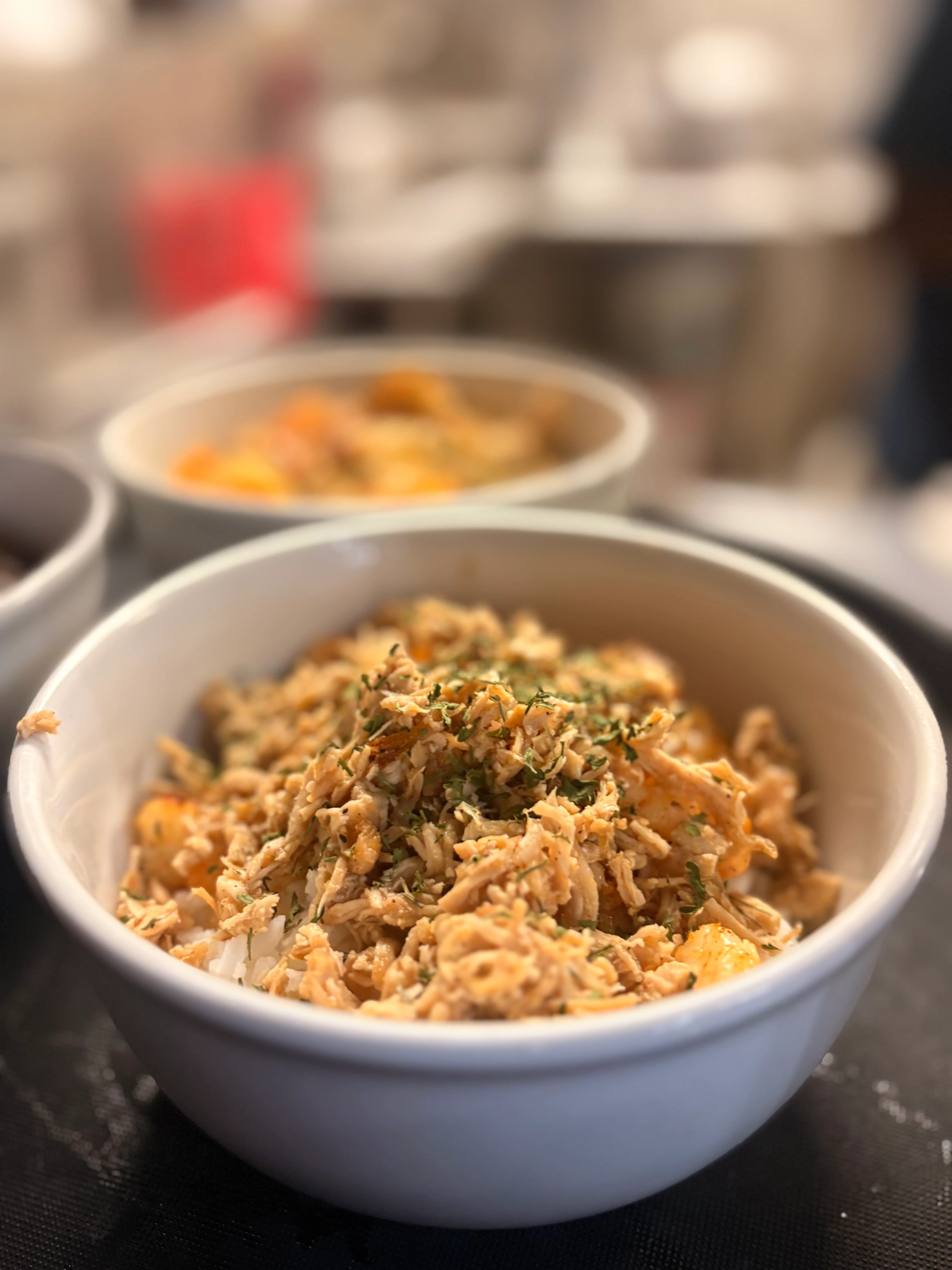 Savory bowl of shredded chicken over rice, garnished with herbs