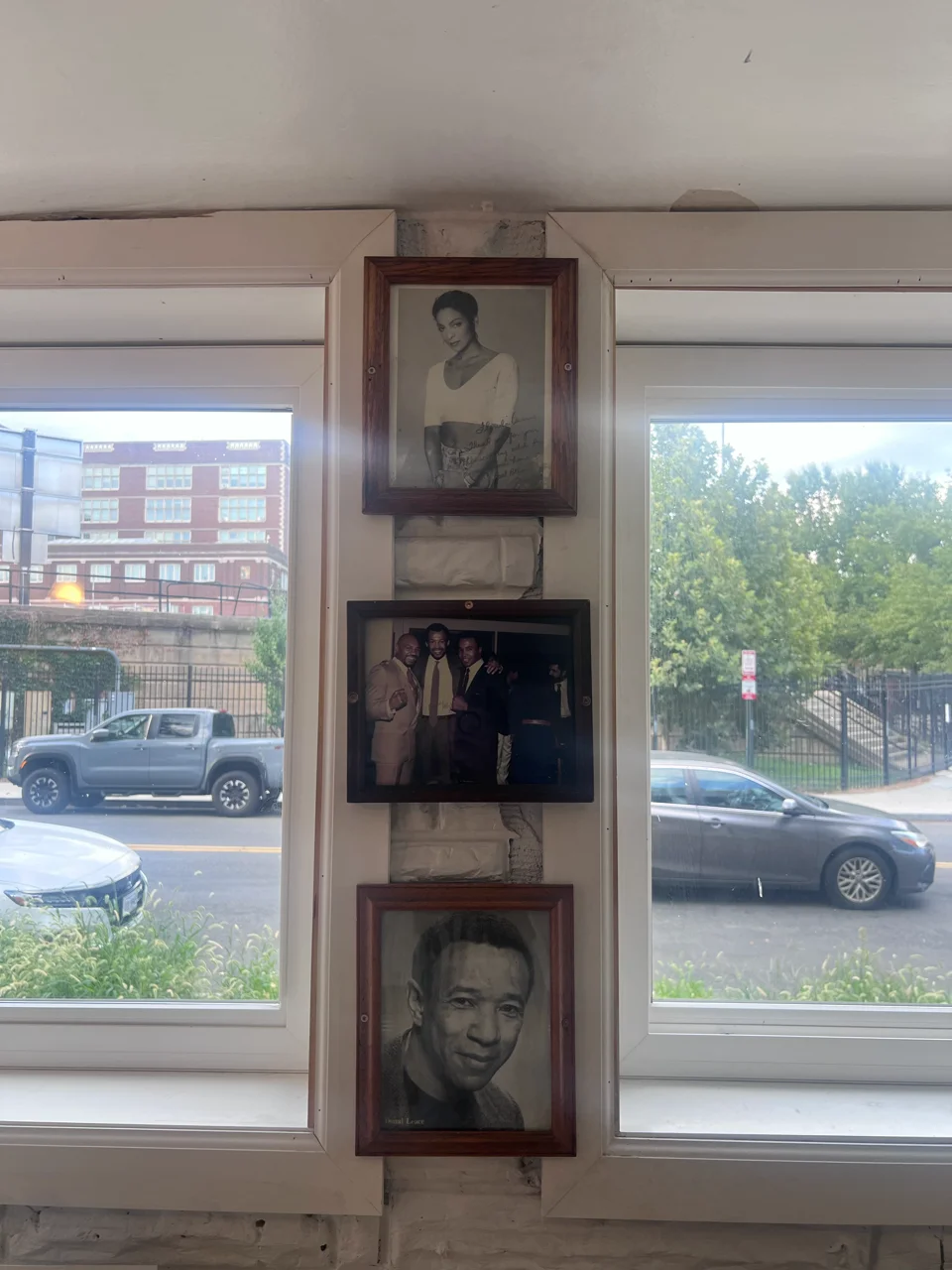 Framed portrait display between restaurant windows overlooking an urban street