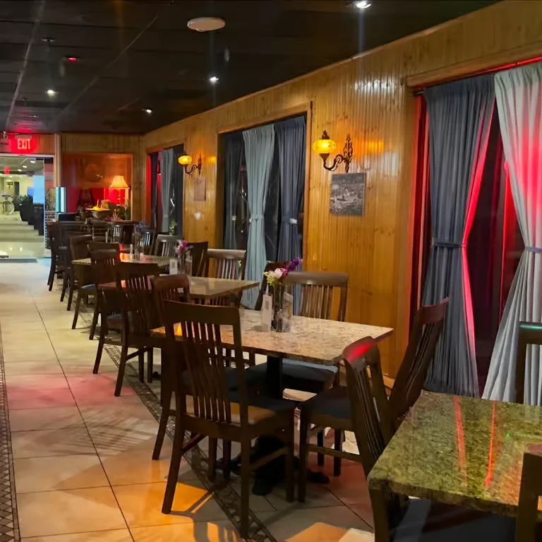The warm and inviting dining room at Aroma Mediterranean Cuisine, featuring wooden walls, granite tables, and cozy ambient lighting.