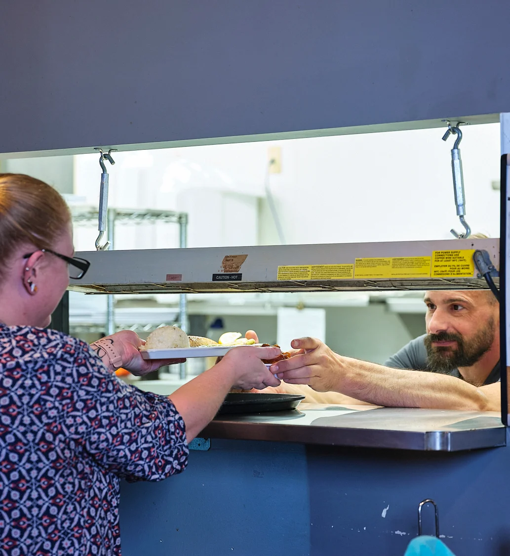 Server handing over a plate of comfort food in a cozy restaurant
