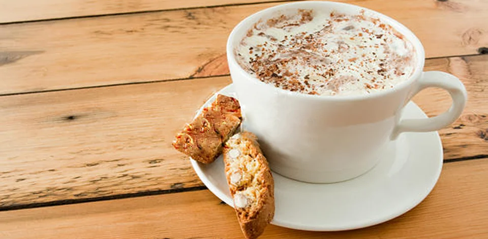 Creamy cappuccino served with biscotti on a wooden table