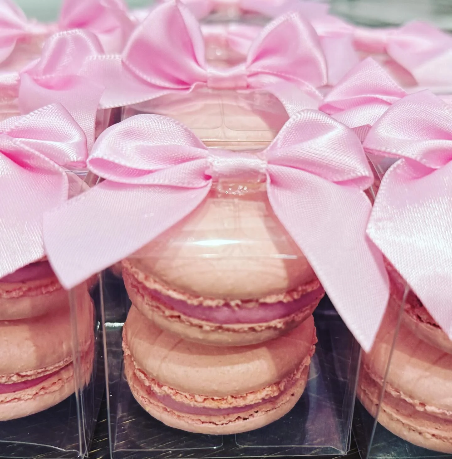 Elegant pink macarons in clear packaging with bows