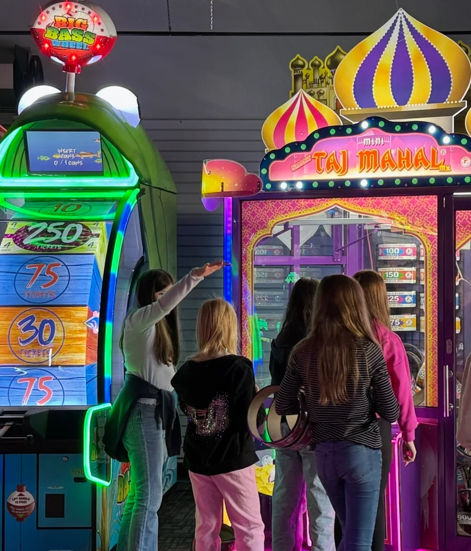 Group of kids playing arcade games in a colorful gaming area