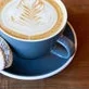 Artisan latte with intricate leaf design and a macaron on the side