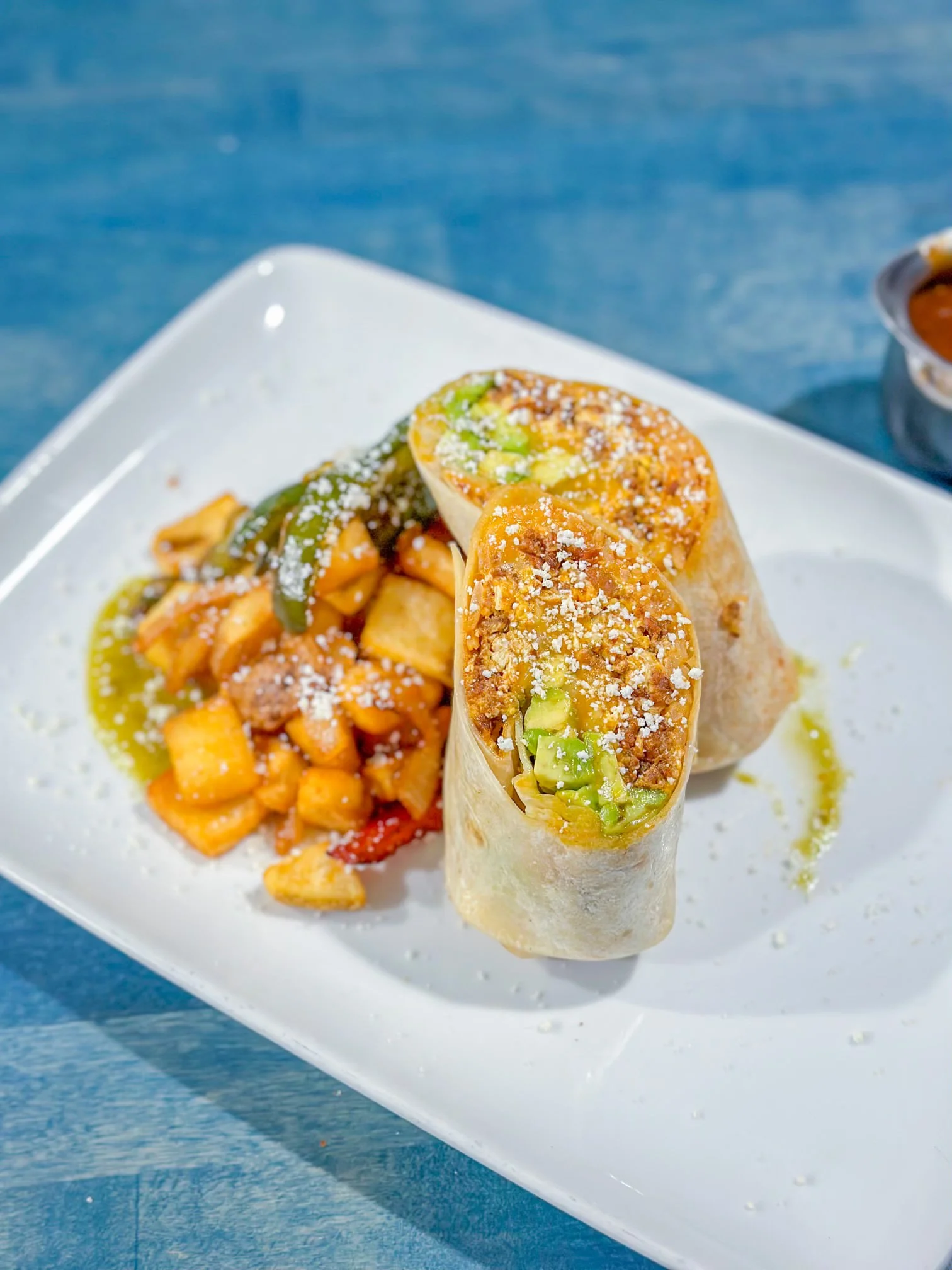 Crispy burrito with savory filling and side of roasted potatoes