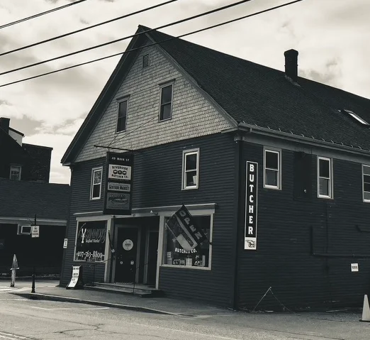 Exterior view of a butcher shop with signage and cloudy sky