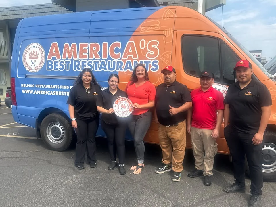 A group of individuals posing in front of a branded van, representing a restaurant promotional event.