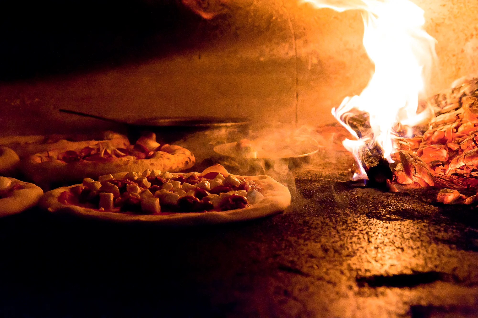 Wood-fired pizza baking in a traditional oven