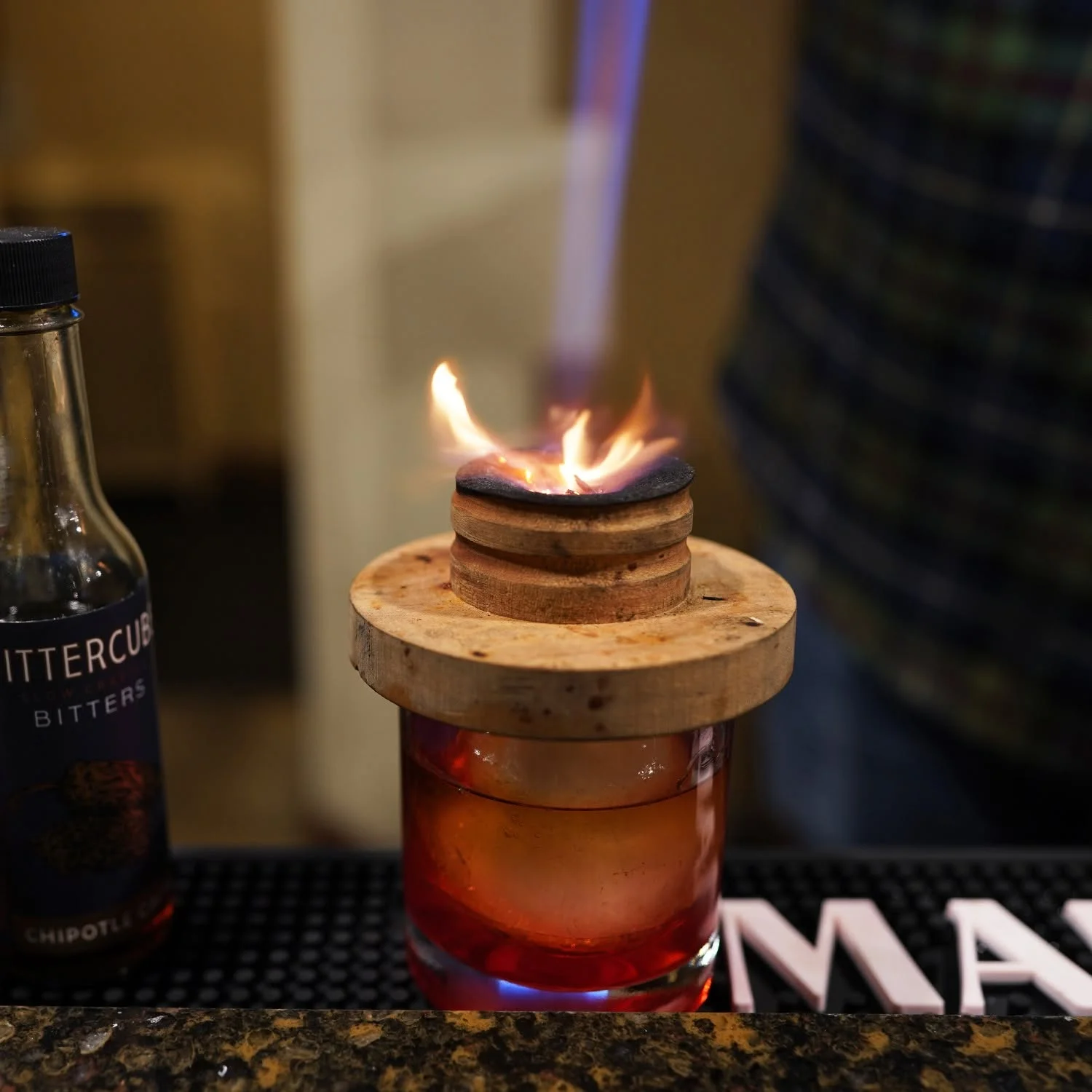Bartender igniting a cocktail with flames at a modern bar