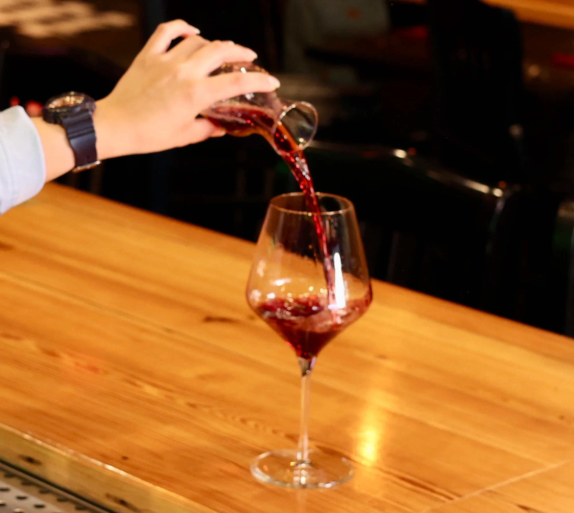 Bartender pouring red wine into a glass at a stylish bar