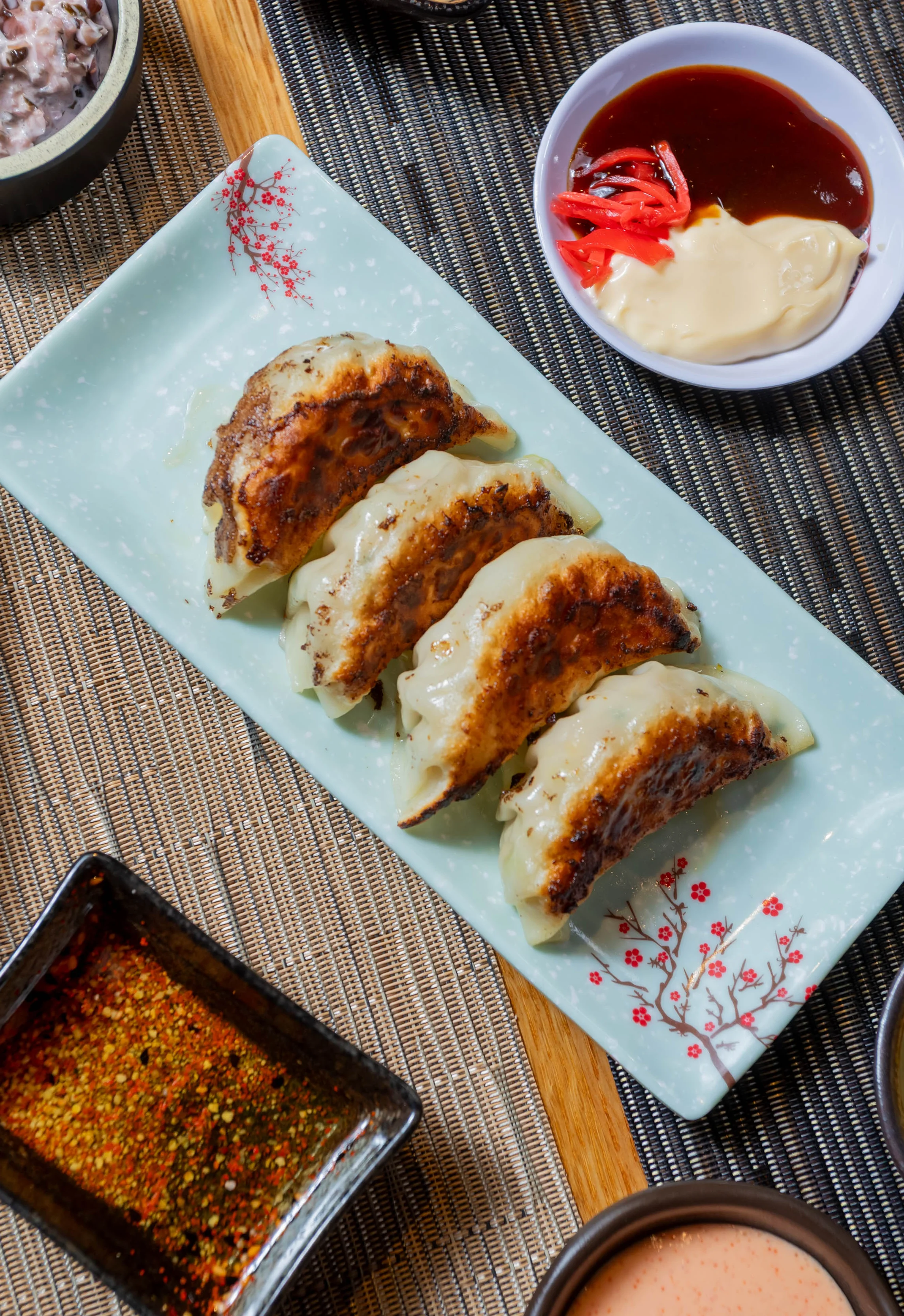 Pan-fried Japanese gyoza served with various dipping sauces