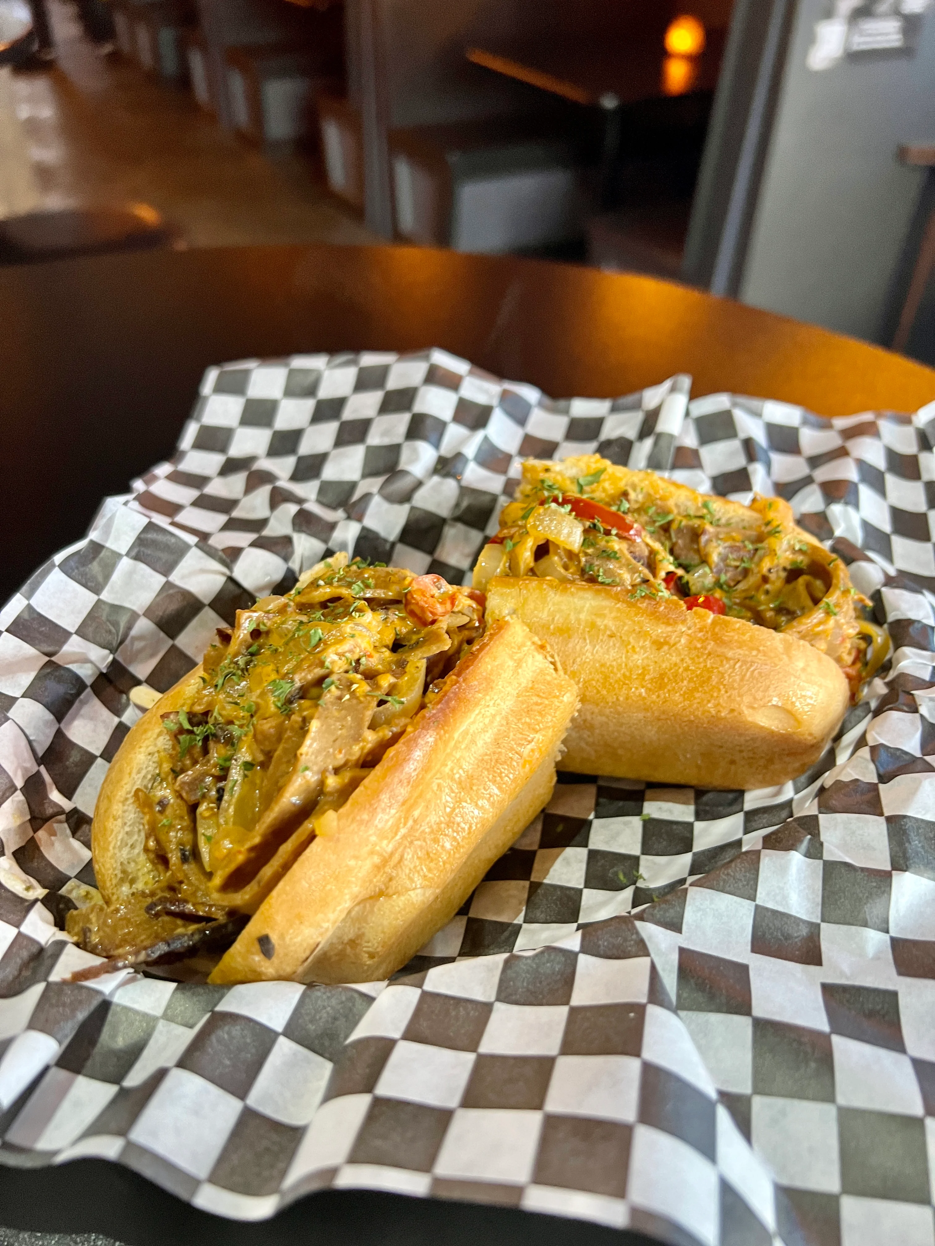 Two loaded hot dogs topped with savory ingredients, served in a checkered basket.