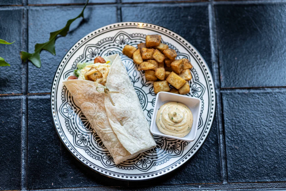 Delicious burrito with seasoned potatoes and dipping sauce