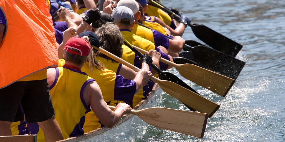 Dragon boat team paddling in sync on a sunny day