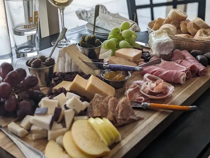 A glass of white wine resting on a wooden table, with utensils nearby, creating a relaxing atmosphere.