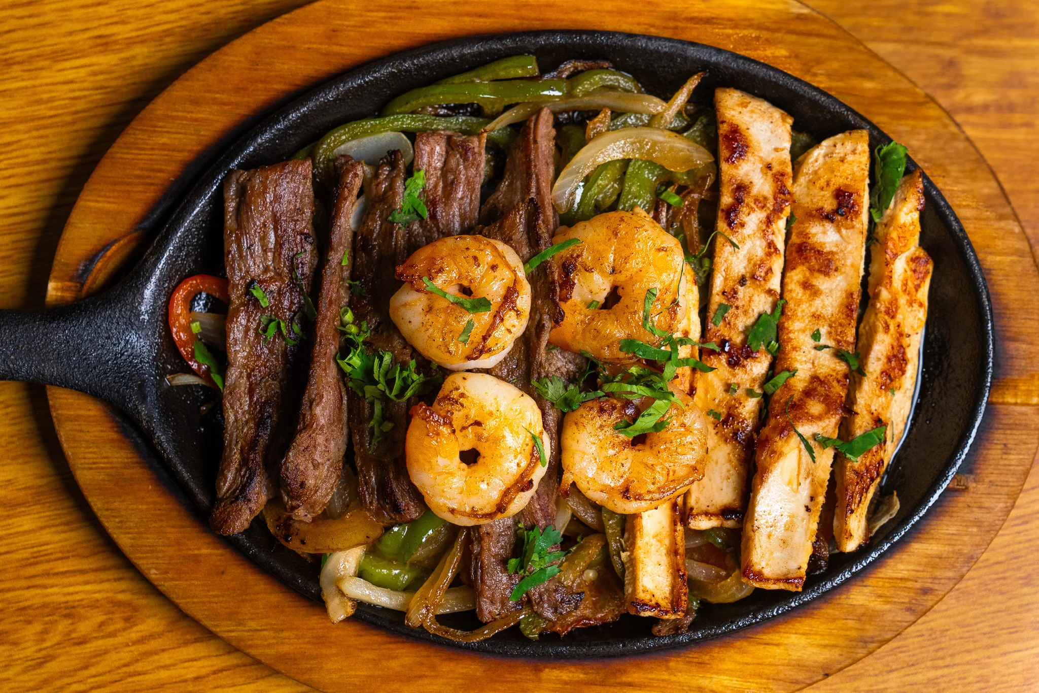 Sizzling fajitas with shrimp, steak, and chicken on a hot skillet