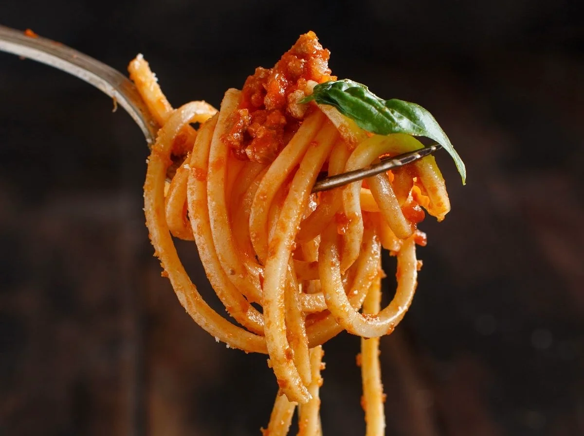 Forkful of spaghetti bolognese with basil garnish