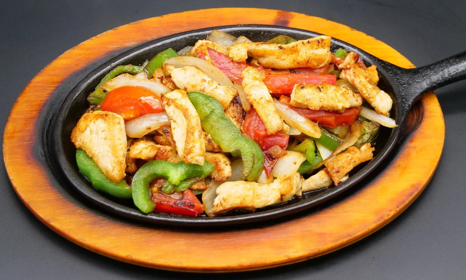Grilled chicken with sauce, rice, guacamole, and fresh vegetables on a plate.