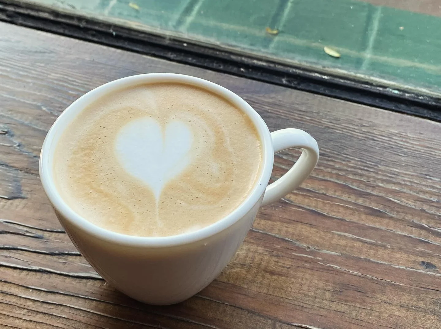 Heart-shaped latte art in a white cup on a wooden table