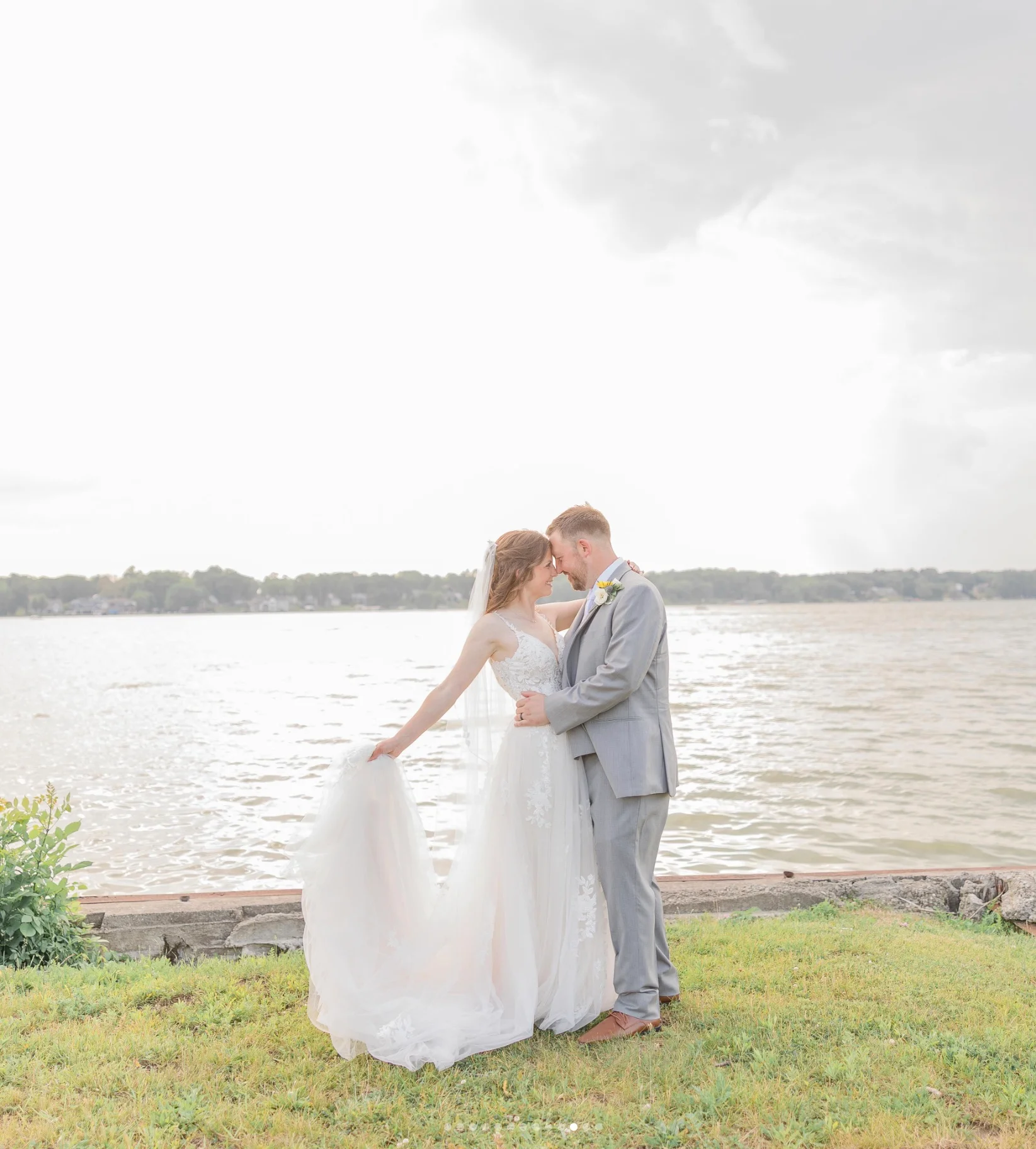 Bride and groom embracing by the lake at sunset